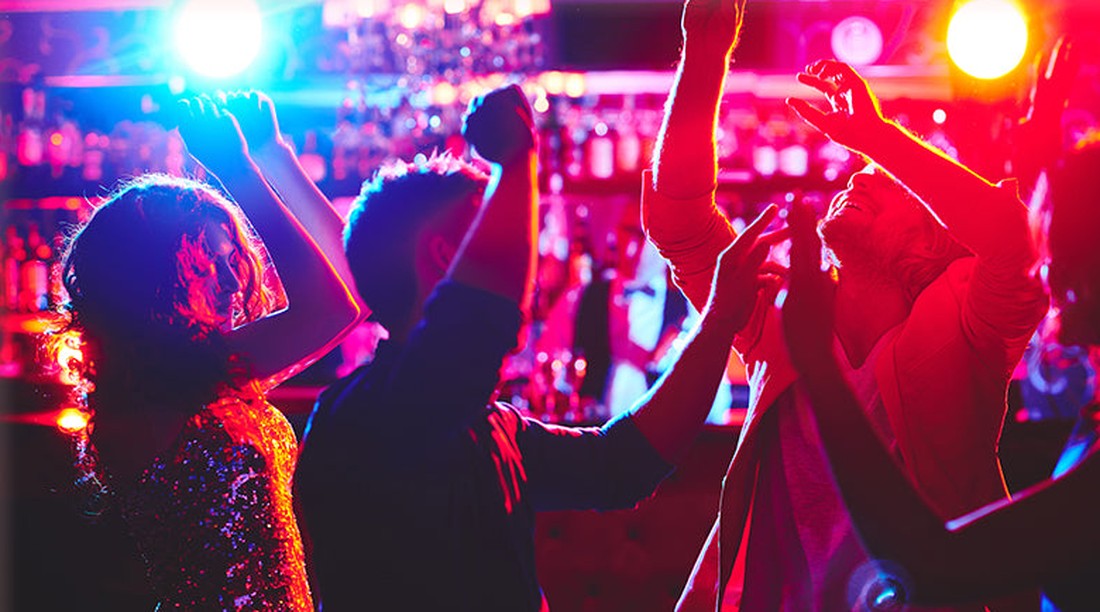 Friends dancing under colourful party lights in a club