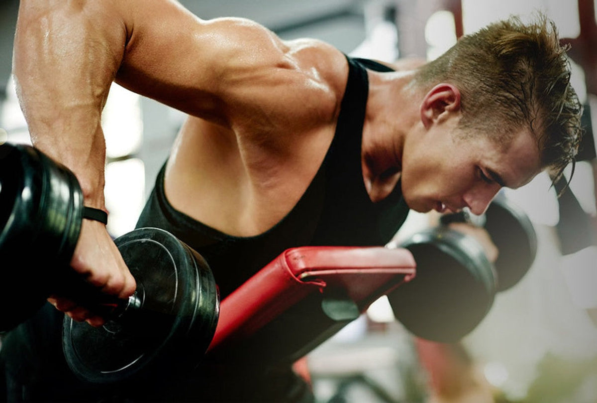 Man in a black Arjen Kroos athletic top training with dumbbells in a gym