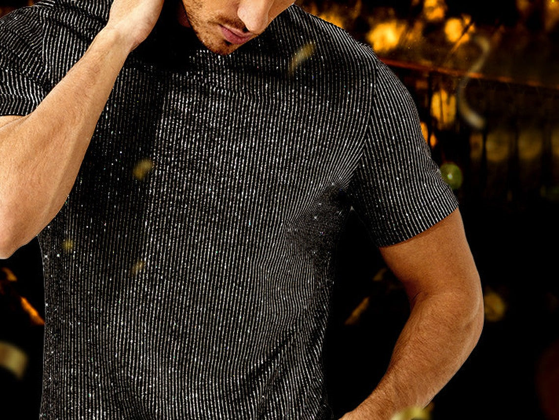 Man in a black Arjen Kroos sequin shirt at a party with warm lights