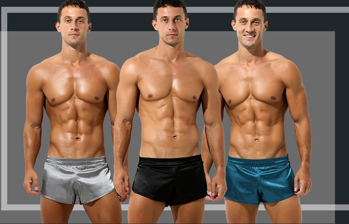 Three men wearing silver, black and teal satin lounge shorts against a dark grey background