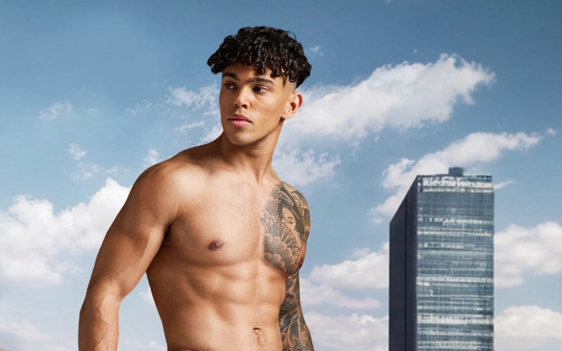 Man on a city rooftop under a blue sky with skyscrapers behind him