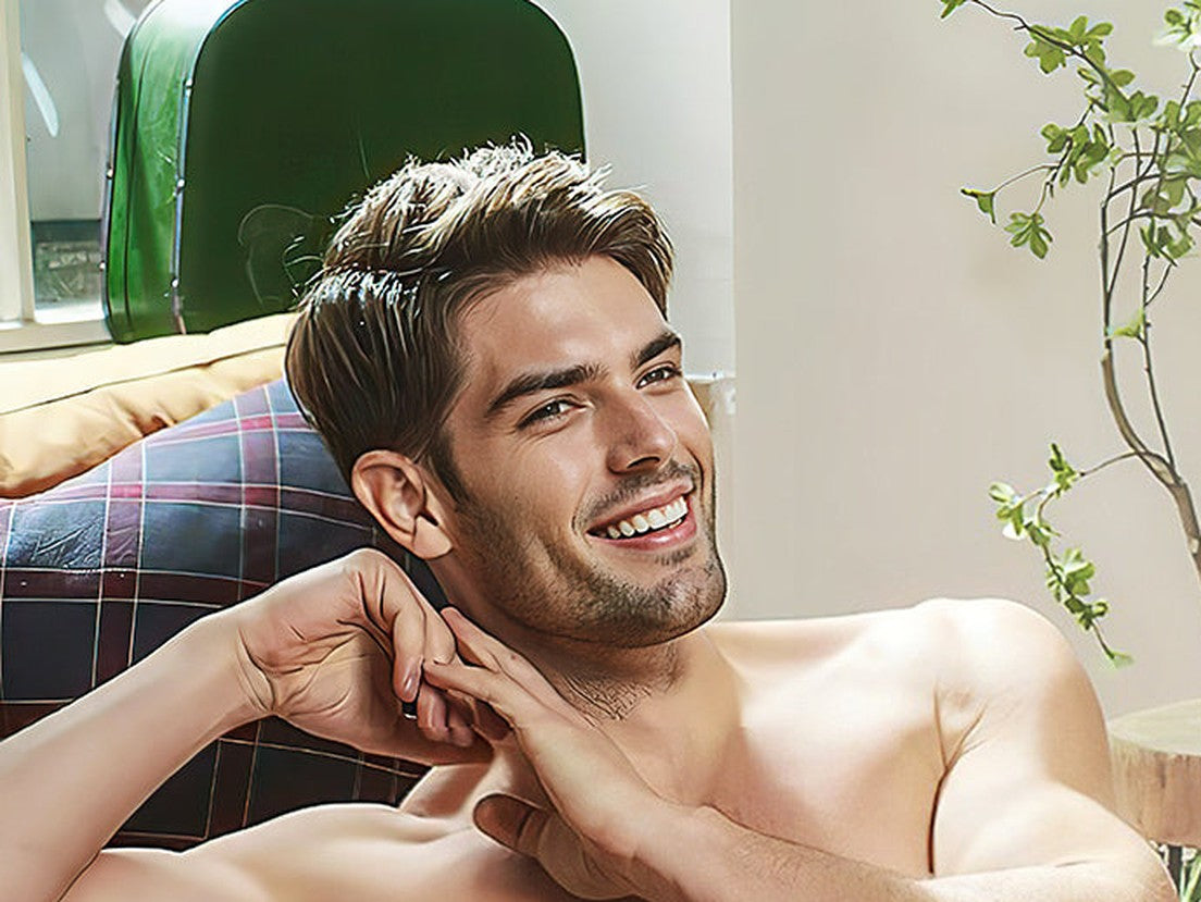 Smiling man relaxing on a sofa at home next to a green plant
