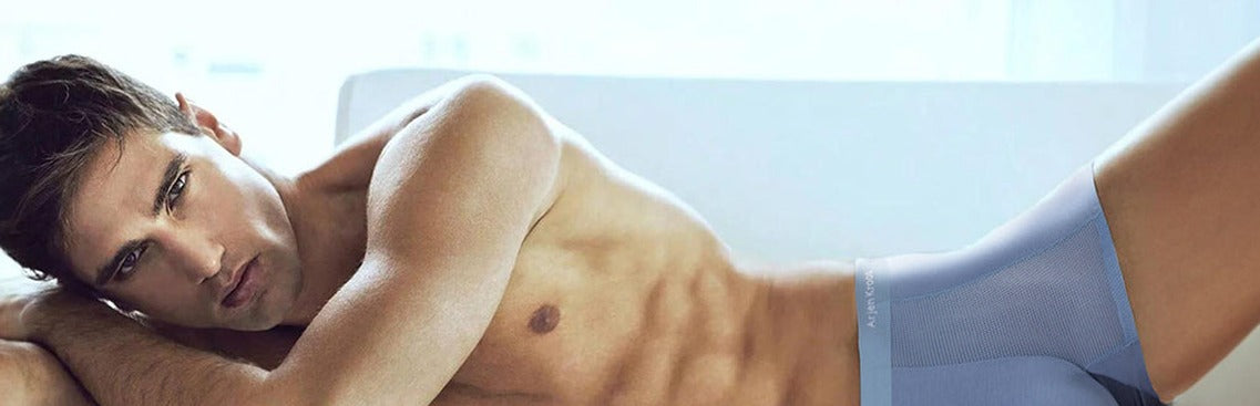 Man reclining on a white sofa wearing blue Arjen Kroos modal boxer trunks